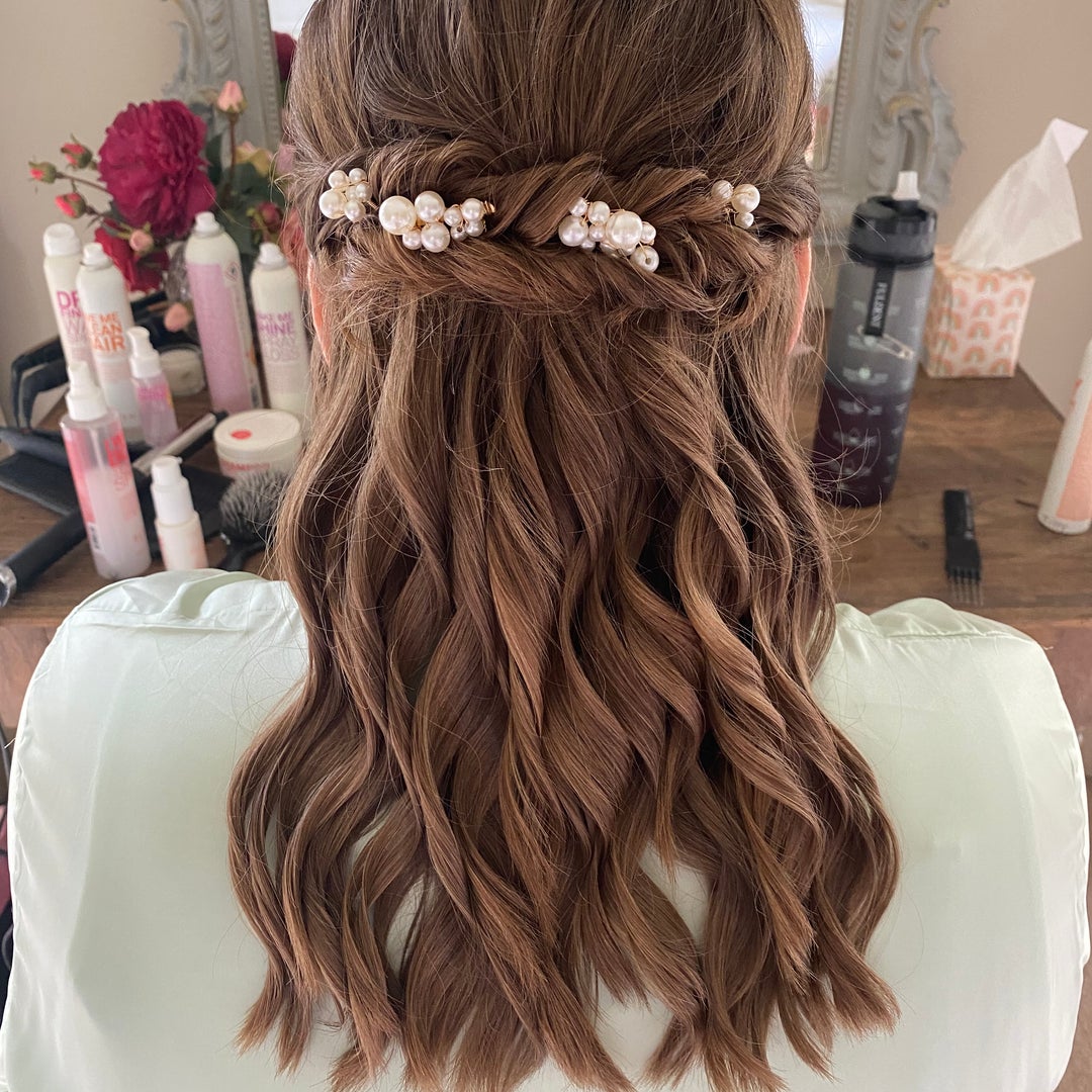 Half-up bridal style with twisted sections and a pearl cluster hairpiece over soft waves
