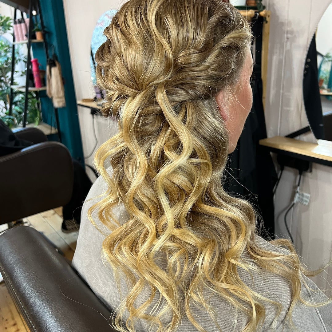 Golden blonde half-up style with twisted crown and loose curls, styled in the salon