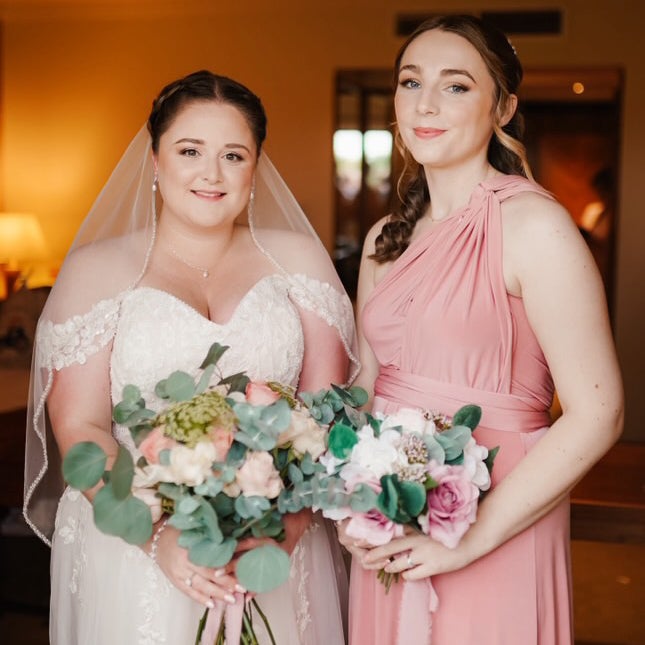 Bride with a veiled updo alongside her bridesmaid, both styled and ready