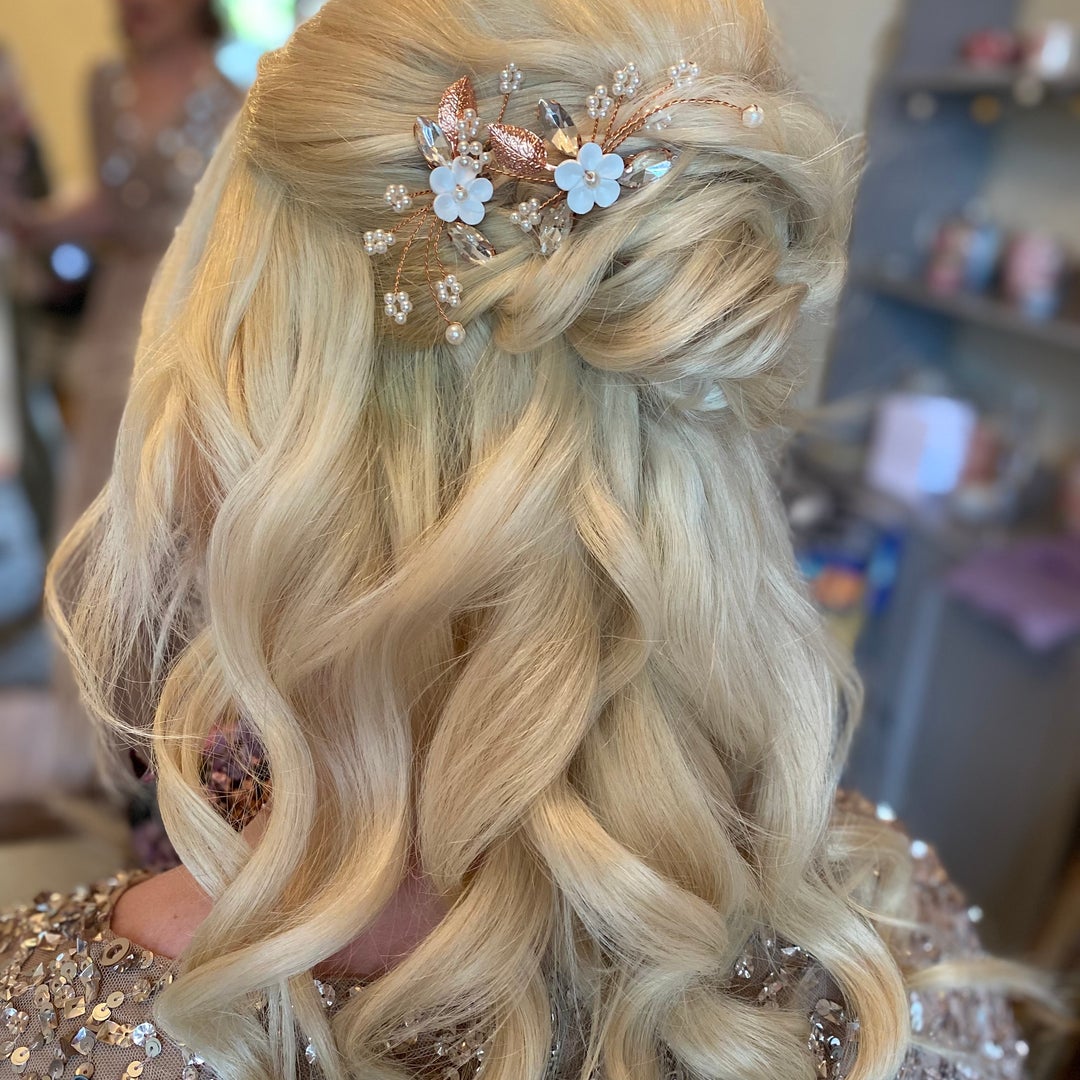 Blonde half-up wedding style with waves and a rose gold floral hairpiece