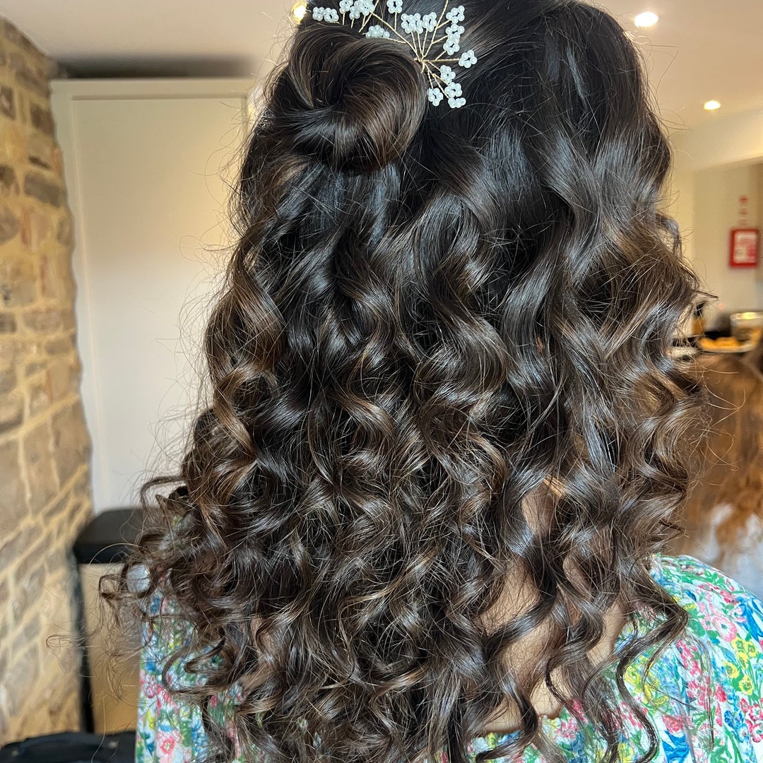Dark curled half-up style with a beaded floral hair vine