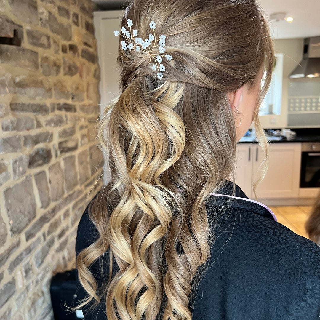 Half-up style with cascading waves and a wired flower hairpin